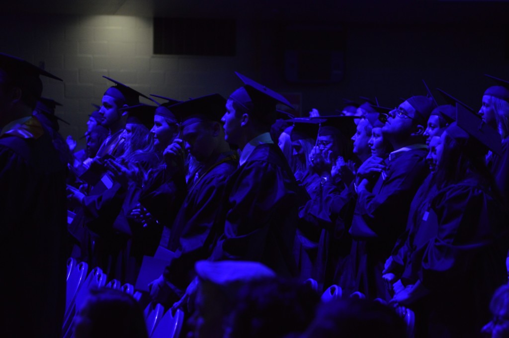 The graduates stand after they receive their degrees and the ceremony nears its end. REID|HARBINGER