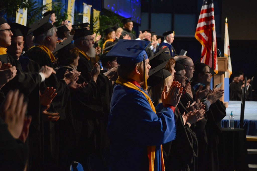 The ICC faculty and staff, lead by student marshal Jordan Barth, center in blue, applaud the graduates after the degrees have been conferred. REID|HARBINGER