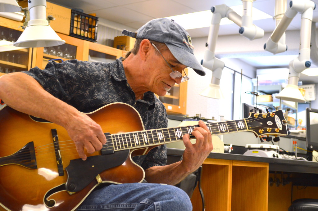 Billy Cook playing one of his handmade arch-top guitars in one of the chemistry labs at ICC. REID HARMAN | THE HARBINGER